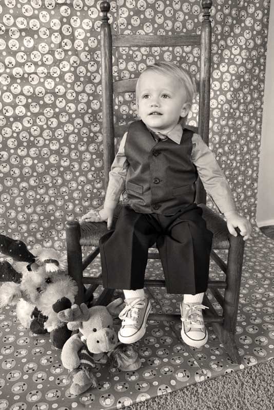 black and white photo of child sitting on rocker next to holiday themed stuffed animals for diy photoshoot at home in dining room by danielle jacqueline photography in olive branch ms