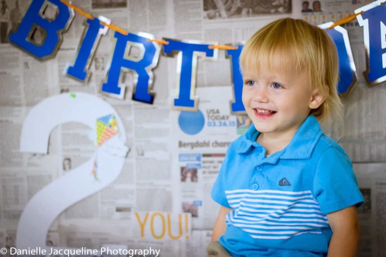 young boy baby blue against #2 newspaper date for birthday backdrop terrible two photo session with danielle jacqueline in olive branch ms