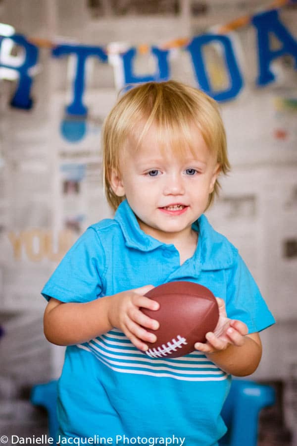 my son in long thought holding little kid's football for terrible two themed portraits by danielle jacqueline photography in olive branch ms