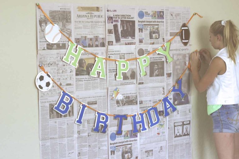 jadynn daughter stringing happy birthday stream across newspaper backdrop for photo session indoors with danielle jacqueline photography diy kids picture ideas in olive branch ms