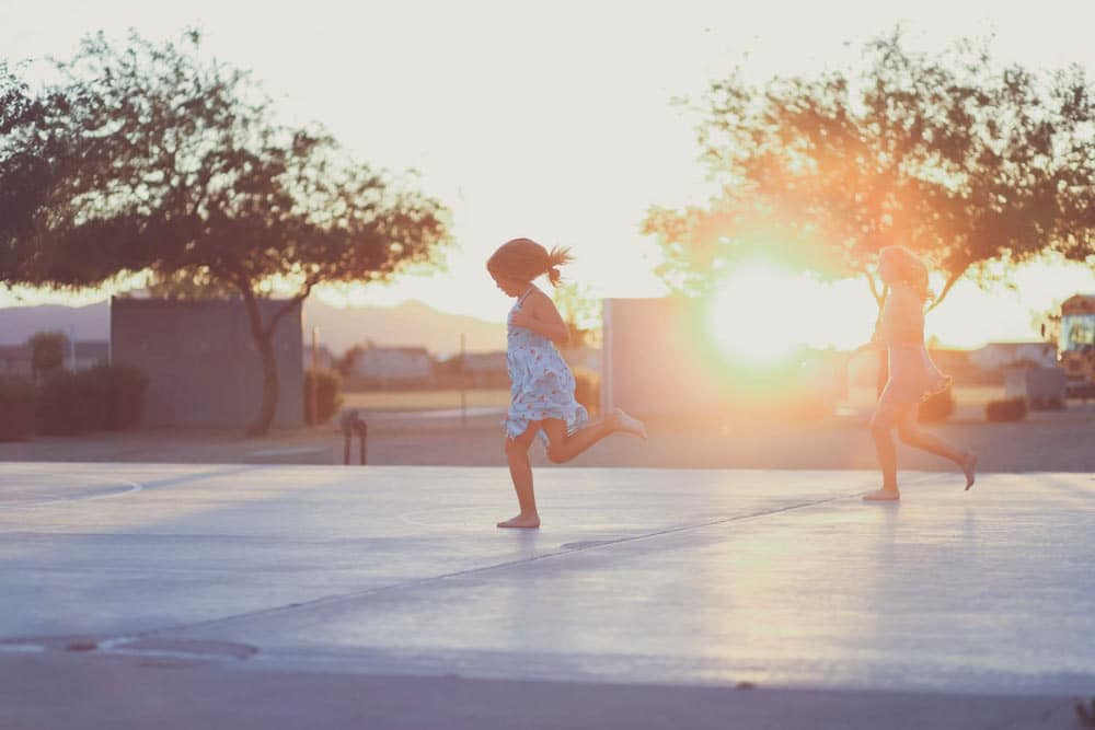 little girl running across pavement at elementary school in sun dress during summer for family outing portraits tips by danielle jacqeline photography in olive branch mississippi