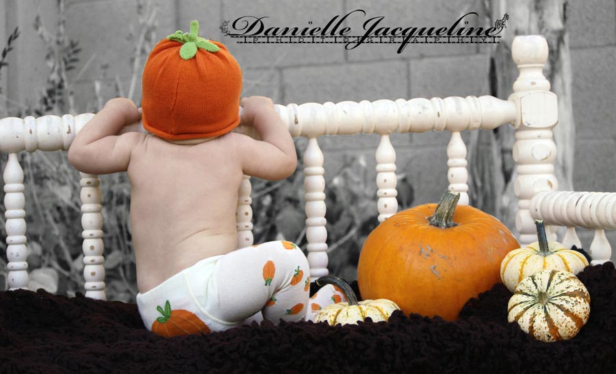 baby boy wearing pumpkin beanie and clothing pulling himself up on white chic bench with orange colors black and white photo edited by danielle jacqueline photography for fall ideas for parents in olive branch ms