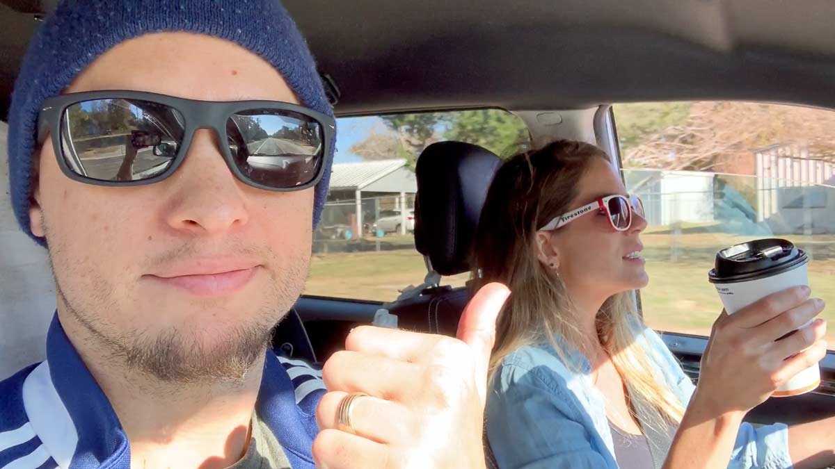 jordan trask pointing at wife danielle in drivers seat singing to radio during cross country family route to indy for thanksgiving travel tips by a photographer in mississippi