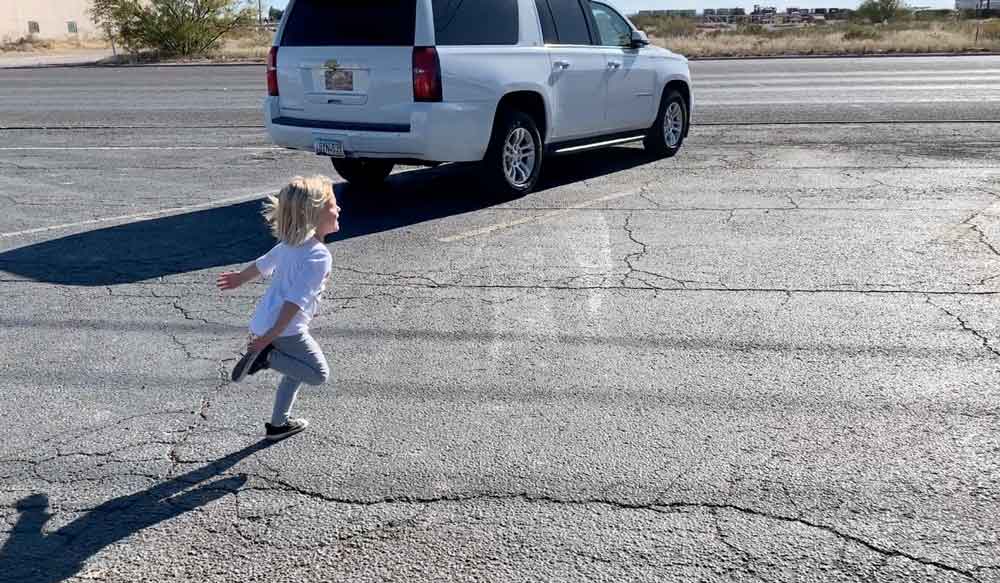 little girl running through parking lot after big meal while on the road with family travel thanksgiving stories by danielle trask photographer in olive branch mississippi