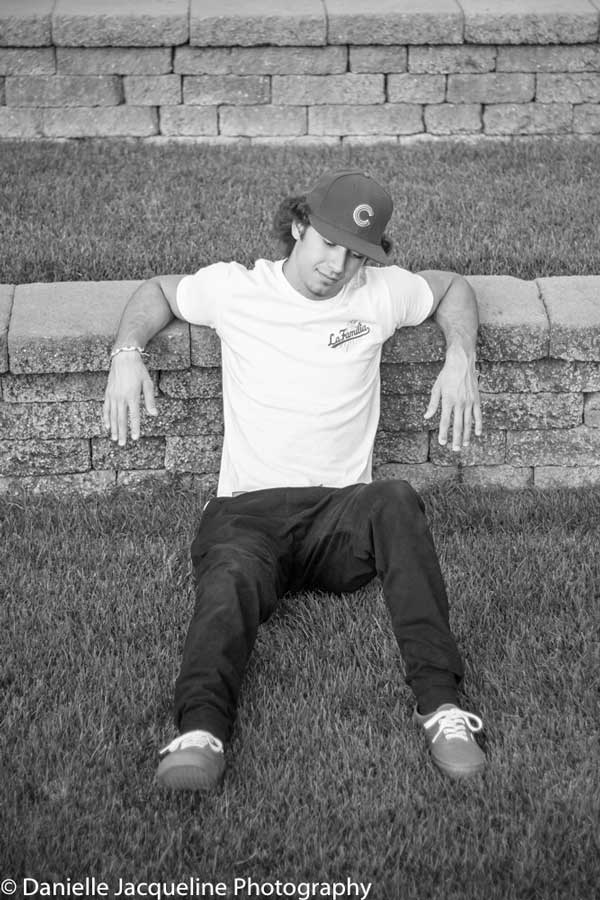 white tee baseball cap lounging teenager for senior photography session with danielle jacqueline black and white steps at park with grass