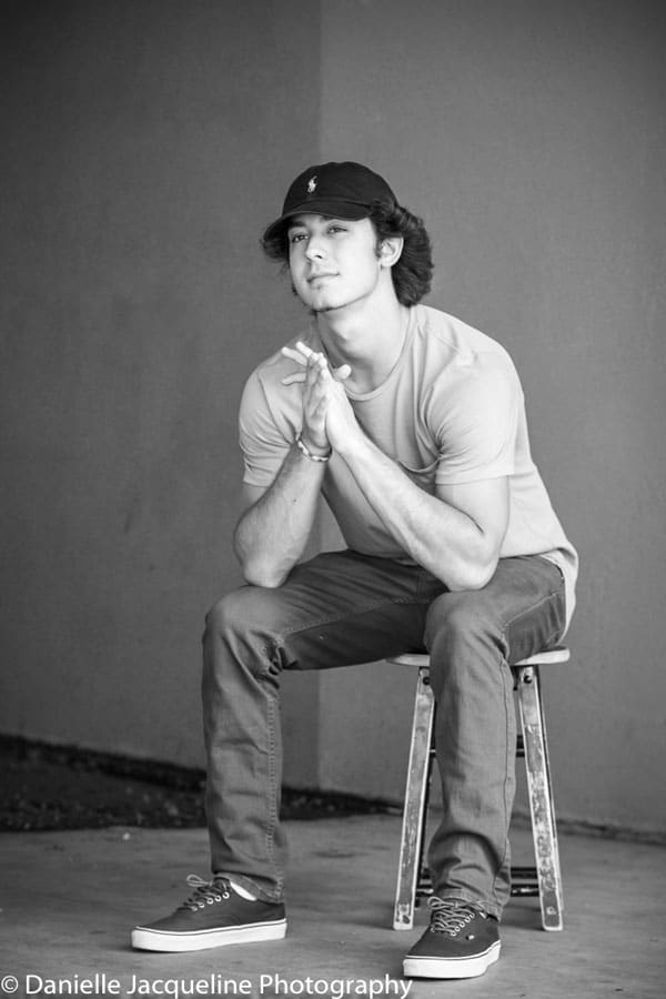 seated on worn stool solo in front of solid wall senior boy portrait ideas with danielle jacqueline photography black and white wardrobe changes olive branch mississippi