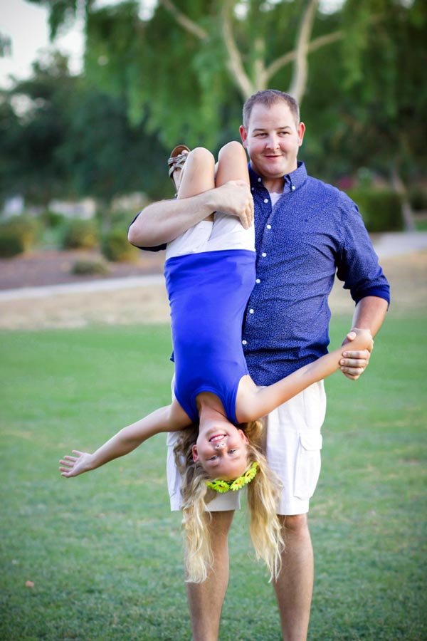 little girl with yellow flower headdress and blue shirt being held by dad at park green grass for unique family portrait ideas in less than 30 minutes during middle of summer by midsouth photograper danielle jacqueline near memphis