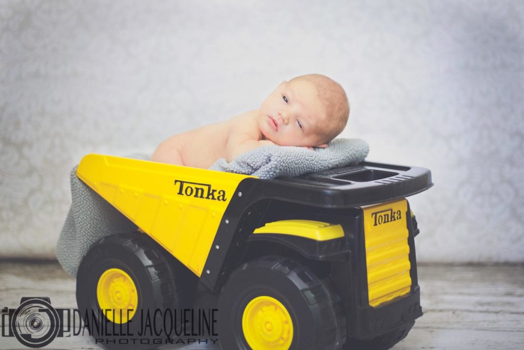 son of first time parents 10 days old laying on tonka truck with blanket during new arrival photo session with danielle jacqueline near memphis ten