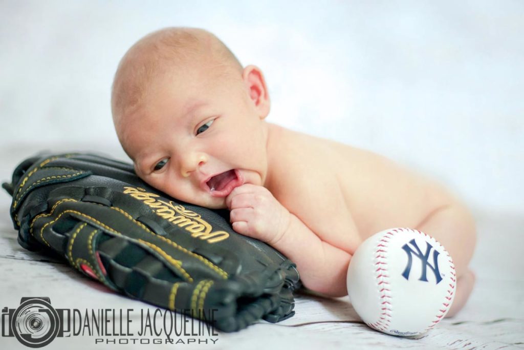 adorable and creative new arrival photo session at studio near memphis tennessee for boys yankees ball and rawlings glove chewing on finger close up with danielle jacqueline