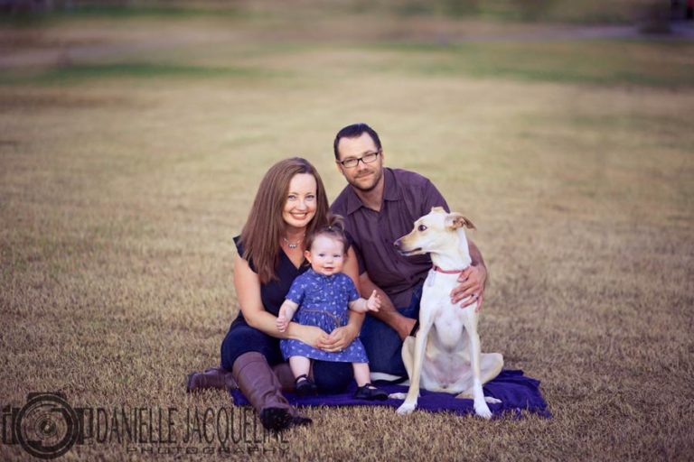 family portrait outdoors in mississippi with dog and 1 year old birthday girl by danielle jacqueline photography seated in grassy area