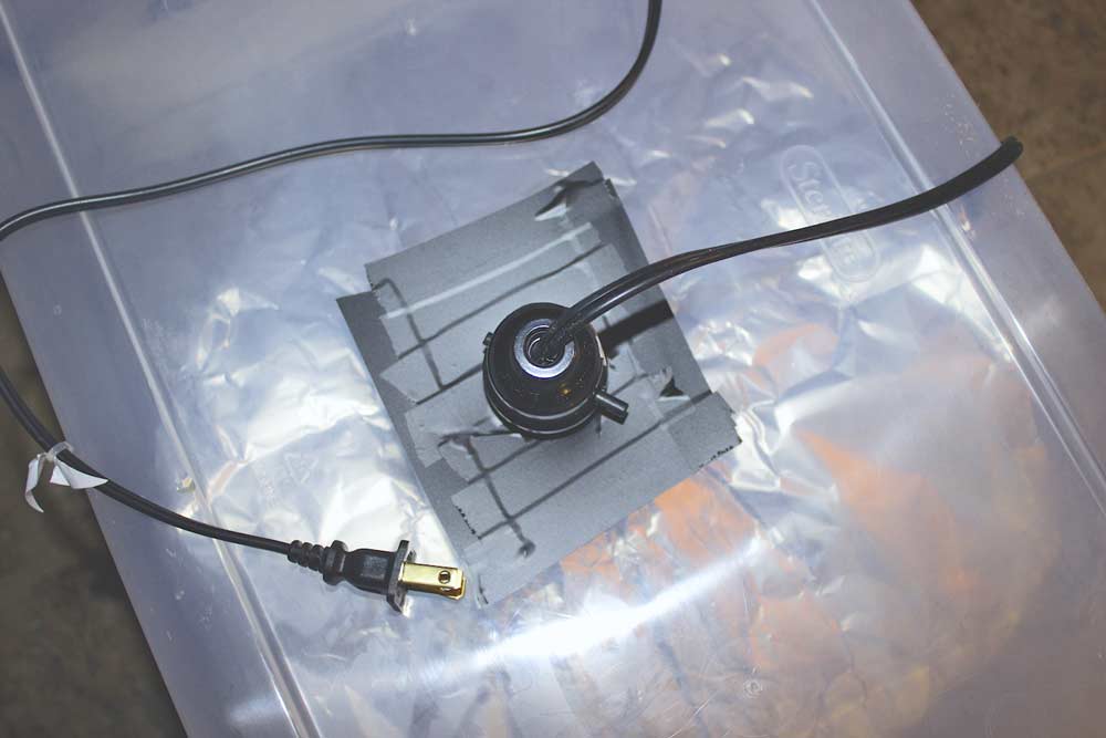 electric tape black used to fasten light fixture onto bottom of plastic storage tub that had hole cut out to make diy studio lighting photography