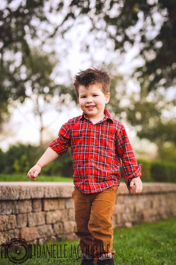 proudly strutting little guy at park in his dress shirt and khakis for junior portraits with danielle jacqueline bright green grass and overhanging trees in december olive branch mississippi