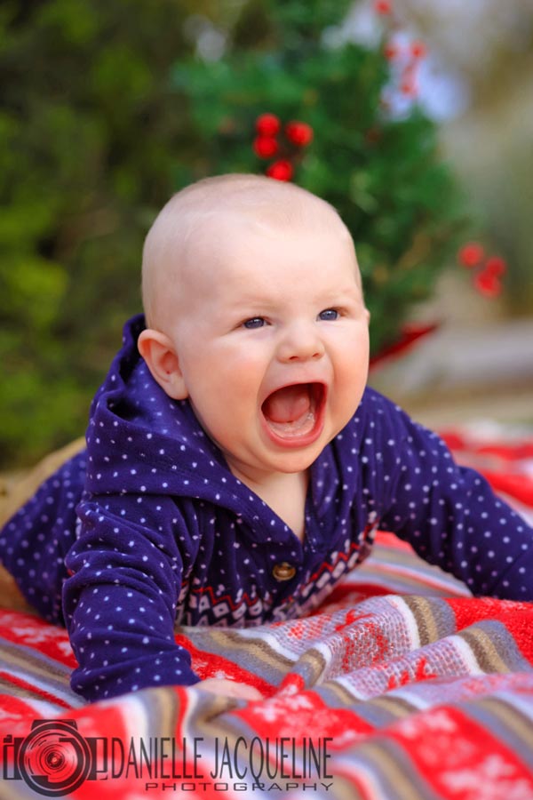 mouth wide open crying little guy laying on stomach in front of xmas tree with holiday themed blanket crying during junior portraits with danielle jacqueline out of olive branch ms