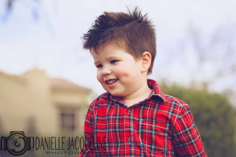 junior portraits close looking up at young boy in red and blue flannel shirt with hair spiked looking towards where he's walking with cute dimples by olive branch ms photographer danielle jacqueline