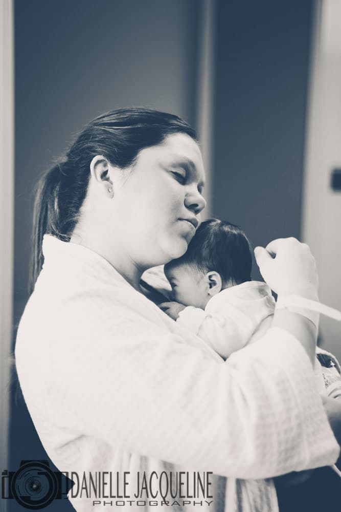 first time mother cherishing authentic moment with newborn baby girl at hospital in robe ponytail captured by fresh 48 photographer near memphis tn danielle jacqueline