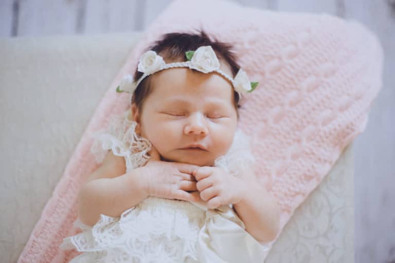 hands folded together little baby daughter sleeping sitting up with white theme and pink blanky in back soft settings at danielle jacqueline's photo studio in memphis tn