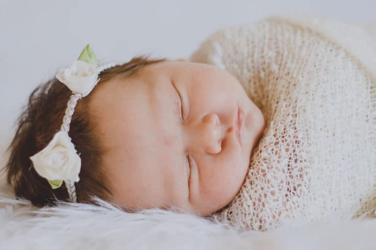 sweet cheeks of newborn baby girl laying on side wrapped in beige blankey at danielle jacqueline photography studio olive branch ms