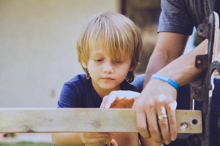 young boy mop haircut blonde using power drill with father to piece together bench in mississippi for blog about growing as a mom with me