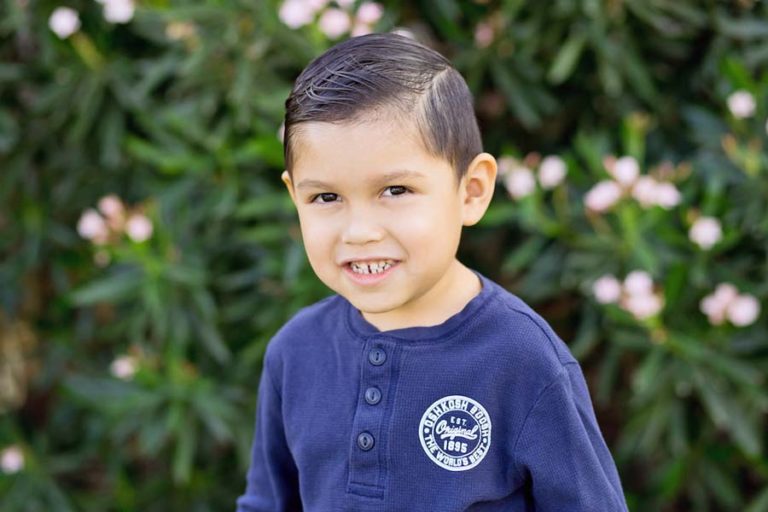 hair combed and learning his smile is this preschool young man in front of natural backdrop in olive branch mississippi for parents