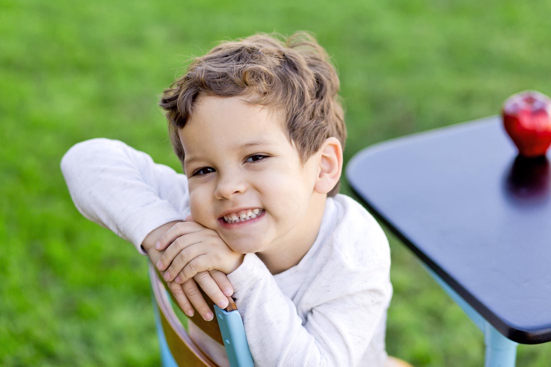 authentic smiles by prek child during outdoor photoshoot with classic desk by danielle jacqueline photography in olive branch ms for back-to-school-pictures