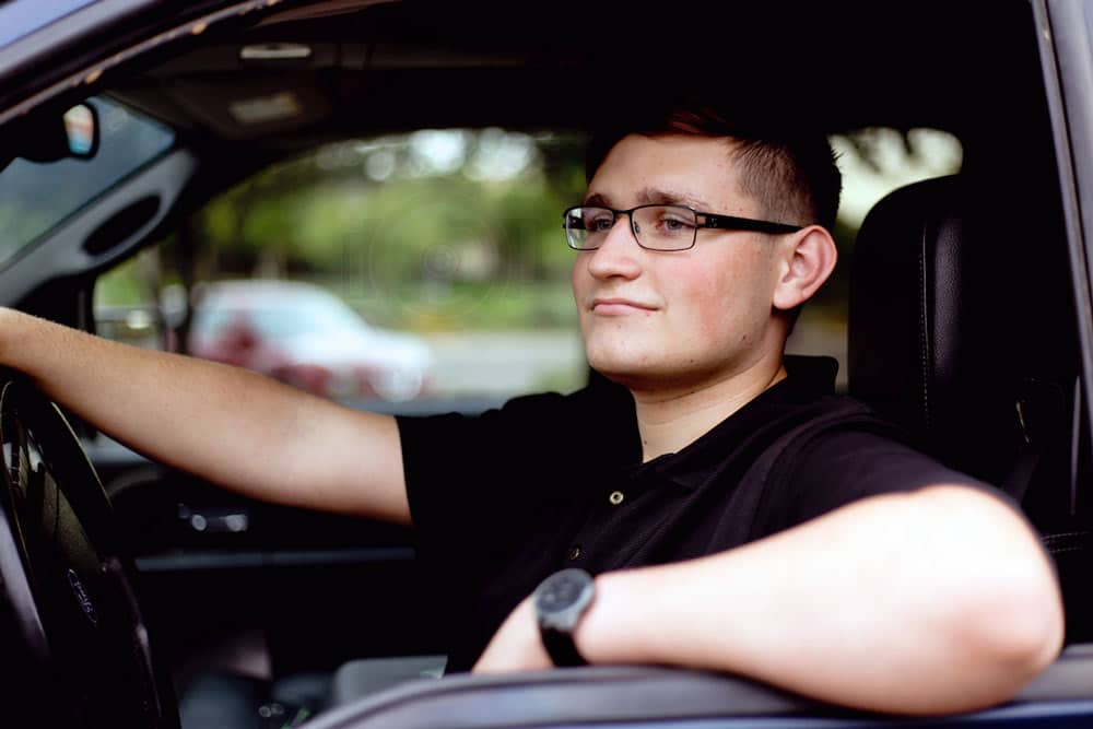 high school senior with hand on the wheel of graduation vehicle during photo session with danielle jacqueline photography near memphis tennessee