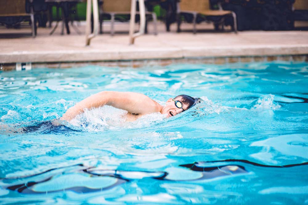 swimming stroke in motion student athlete action shots in water by graduation photographer in desoto county mississippi blue water taking breath while splashing