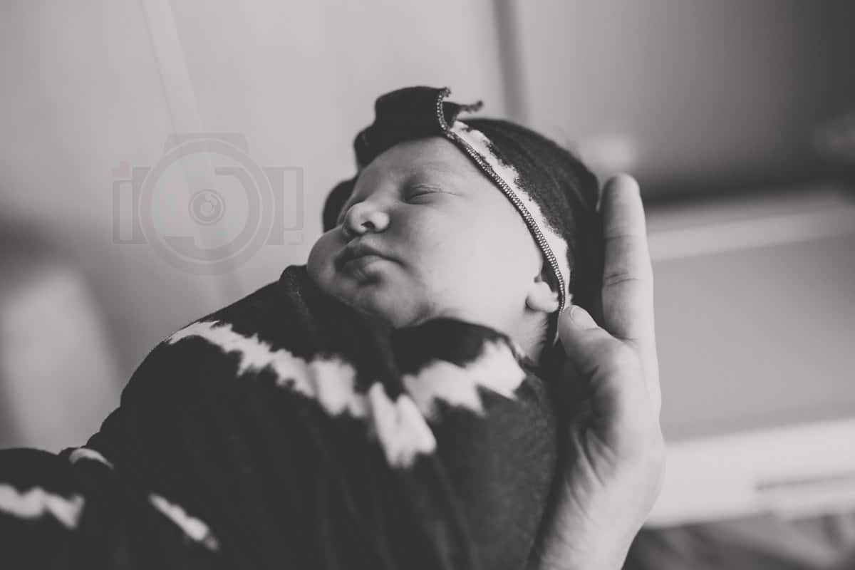 swaddled and sleeping precious new arrival in her daddy's arms at the hospital caught by danielle jacqueline's camera during hospital picture session black and white best in mississippi