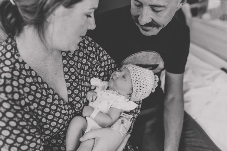 black and white portrait of first time parents looking down at infant daughter mother wearing hospital gown father barely awake but super fulfilled captured by danielle jacqueline photography in south eastern memphis area