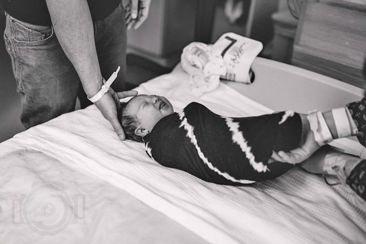 crying baby being swaddled in hospital fresh 48 session with danielle jacqueline black and white as they change outfits for olive branch ms portraits for parents