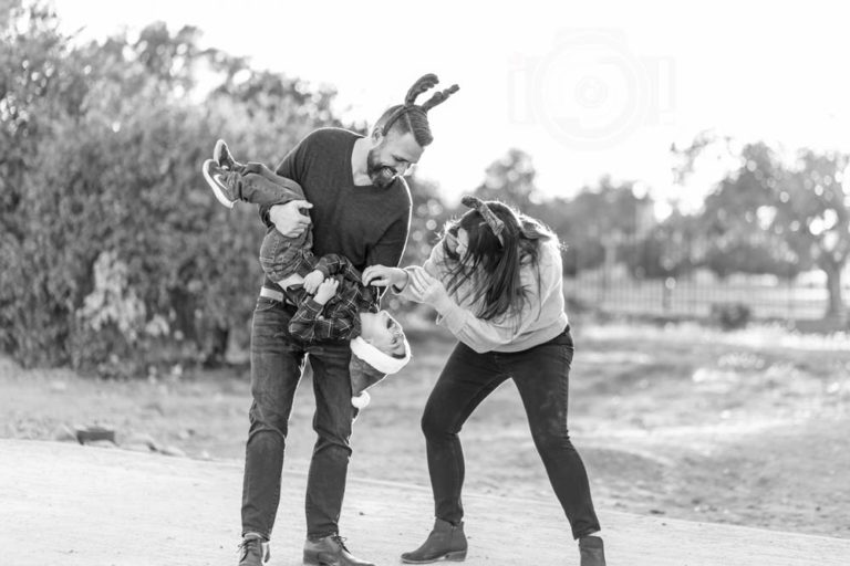 black and white photo of father dumping son upside down while mother tickles him and they all laugh captured by mississippi photographer danielle jacqueline