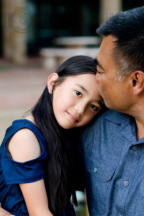 close up of smallest daughter getting kiss from dad during family shoot during father's day outside with denim blue theme with danielle jacqueline in olive branch ms