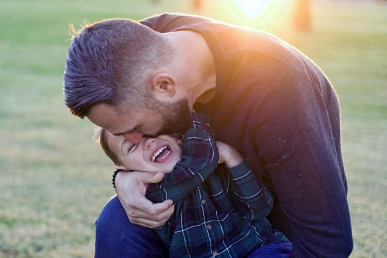 loving father holding son in middle of grassy area before christmas holiday during family photoshoot with danielle jacqueline in olive branch ms