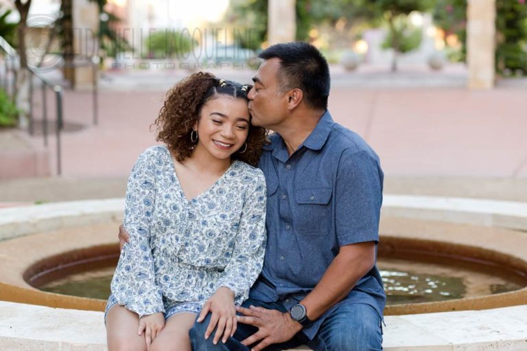 kissing oldest child and daughter on forehead during duet portraits for father's day photography session at courtyard outside with bricks and blue wardrobe with danielle jacqueline olive branch ms