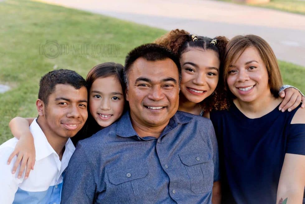 father's-day-photography-session-by-danielle-jacqueline-with-dad-in-middle-of-two-daughters-with-special-needs-son-on-left-and-wife-on-right-in-front-of-grassy-area-at-local-park-germantown-tennessee