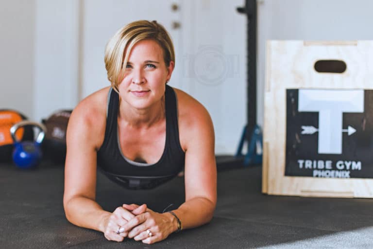 female fitness center owner in plank position at gym with kettle bells in background with box jumping station and squat rack showing in perspective moment with expert during training photo by danielle jacqueline photography serving olive branch ms and southeast memphis