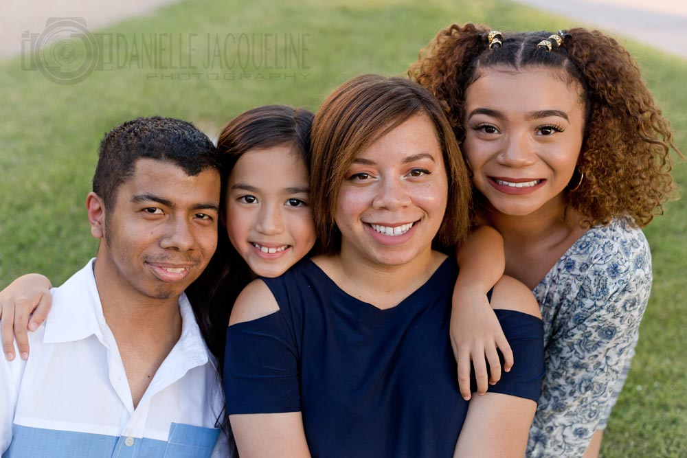 beautiful family picture in front of strip of bright green grass showing navy blue and white color theme of mom and kids short to tall portrait by danielle jacqueline for contact page in memphis tn