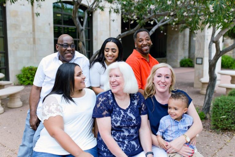 awesome interactive family photo with siblings and grandchildren showing third generational tree all looking at each other in public urban setting memphis tn at table with trees in the background corporate building photography by danielle jacqueline color