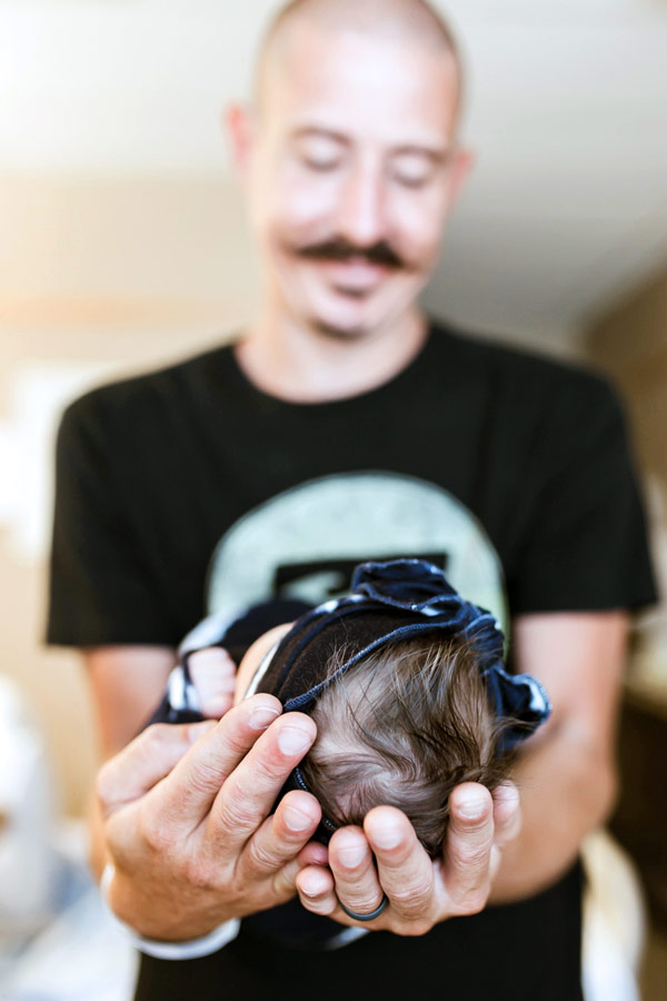 father's hands extended towards camera in focus with daughter's head of hair looking down at baby blurred face during hospital photography session first 48 hours by danielle jacqueline southeast memphis tn