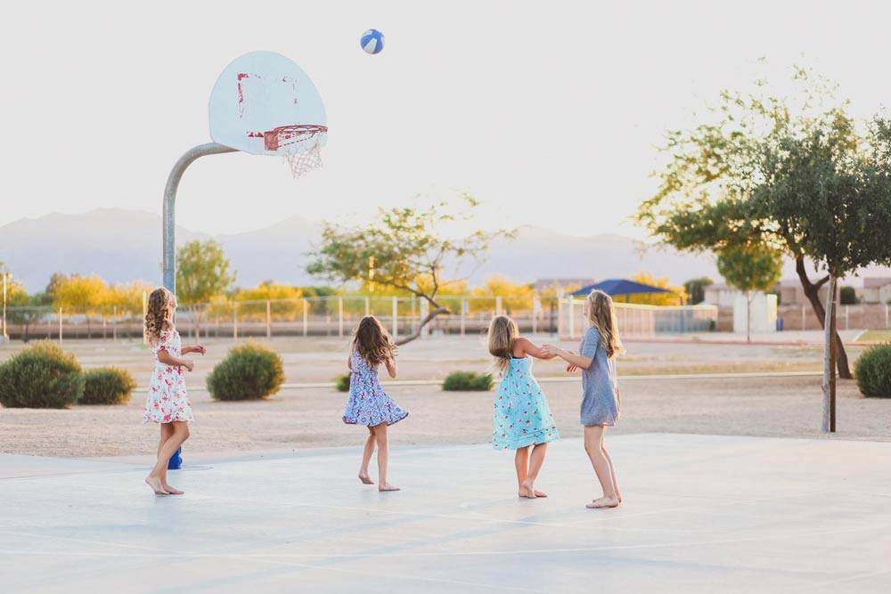 middle school girls playing basketball outdoors at playground courts golden hour in dresses after awards ceremony back-to-school pictures professional kid's photographer in memphis tn