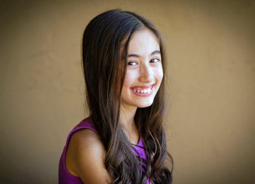 elementary school graduation portrait for little girl daughter wearing purple attire long hair big smile eye contact comfortable brown background outdoors for parents in memphis tenn