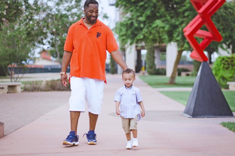 orange polo shirt white shorts air jordans hand on young son's head as they walk down sidewalk quality time park memphis tenn by danielle jacqueline photography color