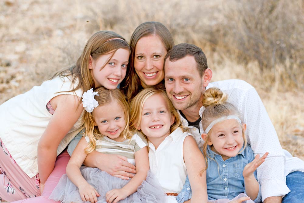 lots of personality in a family portrait outside unique smiles of mom and dad with four girls taken by danielle jacqueline photography now located south of memphis tennessee