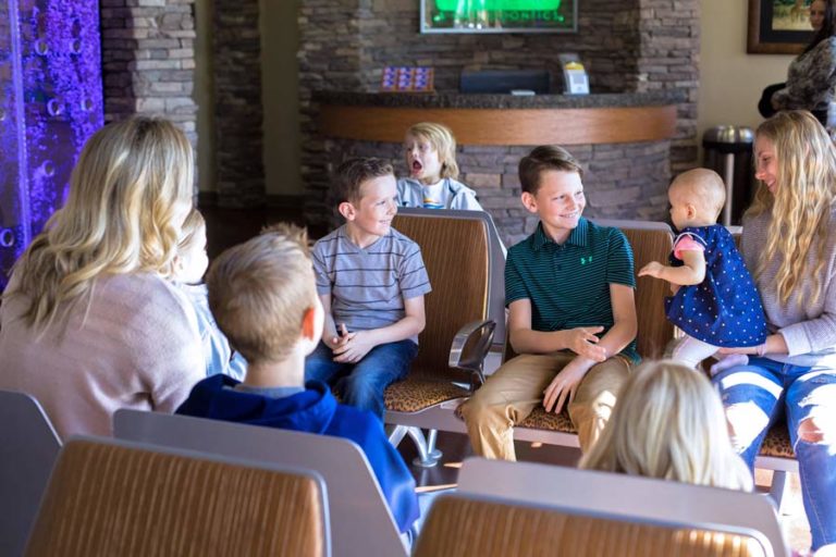 kids sitting in waiting room at doctors office during photography shoot with professional local danielle jacqueline of olive branch front counter in background older children interacting with baby pediatric clinic