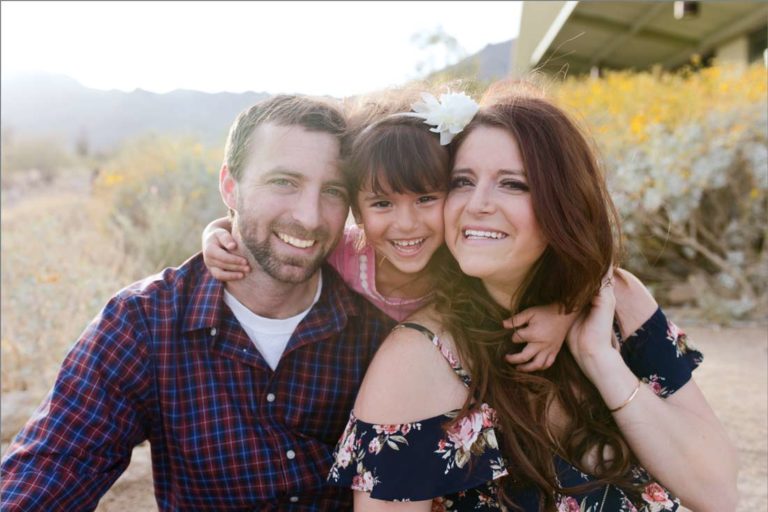 adorable little girls looking straight at camera in between parents in love during outdoor family portraits formal with danielle jacqueline photography now in desoto county mississippi