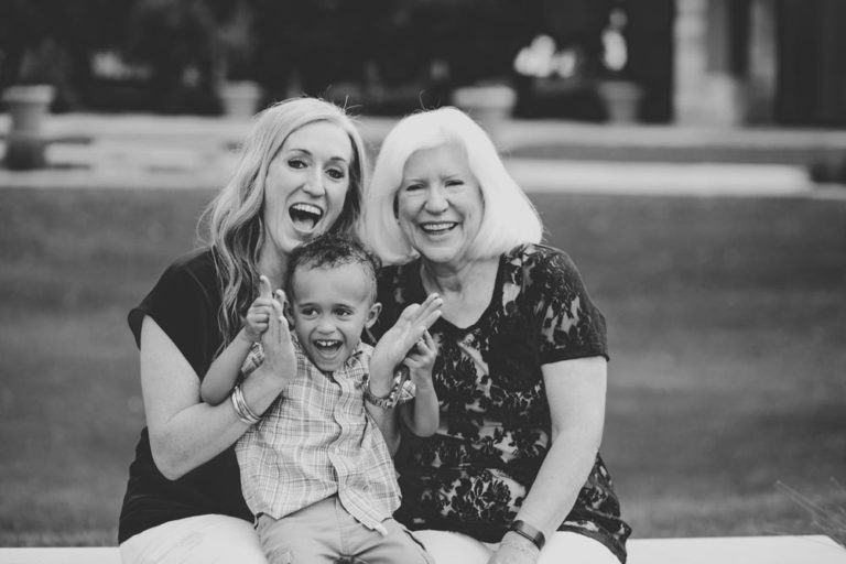 excited momma trying to engage young son on her lap while sitting next to mother grassy background candid moment family picture worth keeping black and white by danielle jacqueline in desoto county ms