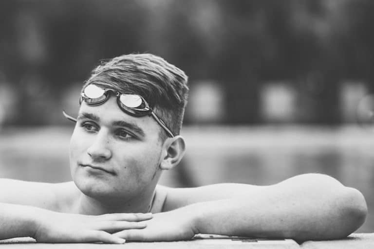 close up of high school swimmer while posing in pool for graduation photos with parents and danielle jacqueline in olive branch ms