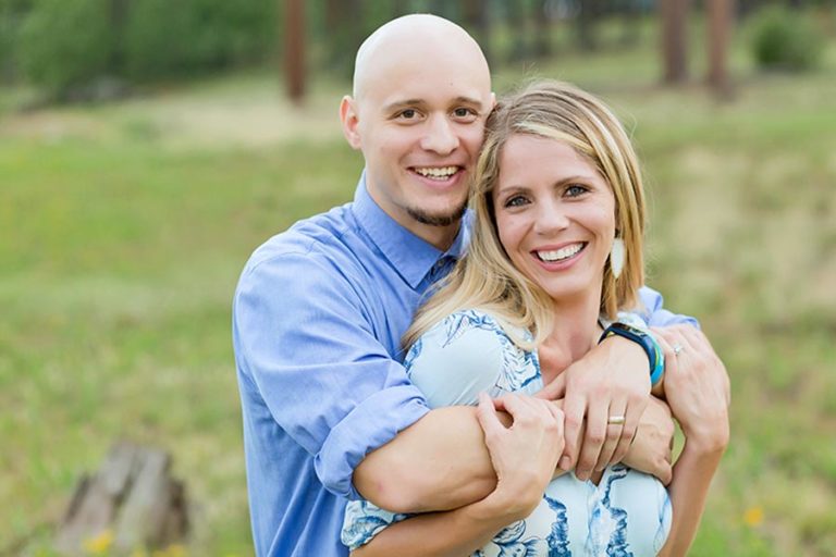 jordan co owner of danielle jacqueline photography hugging wife during photoshoot in olive branch mississippi with baby blue theme and grass background by lake professional michelle praskins