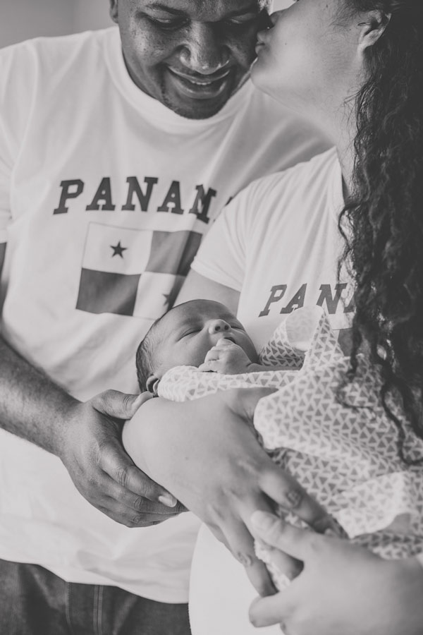 parents loving on each other while holding their first born son born in america from panama t shirts kiss on cheek by olive branch ms photographer danielle jacqueline