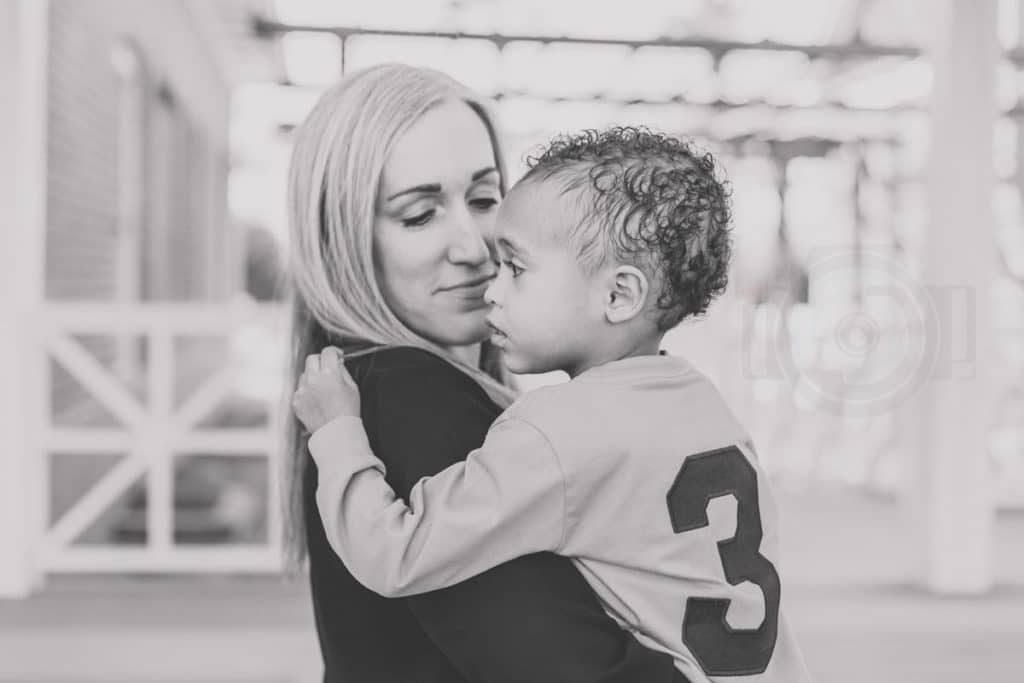 adoring mother looking curly haired son in the eyes during difficult family photo session where child wouldn't sit still great direction from desoto county photographer black and white imagery with country setting candid