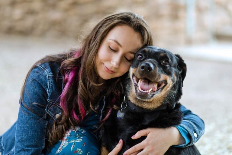 jean jacket wearing young woman brunette with pink highlights hugging black lab dog pet photography services by danielle jacqueline in memphis city park on steps during southern fall girls best friend